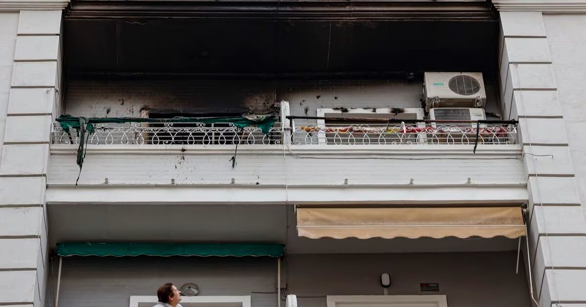 Una mujer observa desde su balcón el piso superior, en el número 51 de la calle Salamanca de València, donde esta madrugada se ha declarado un incendio en el que ha fallecido un hombre y dos mujeres han resultado heridas.