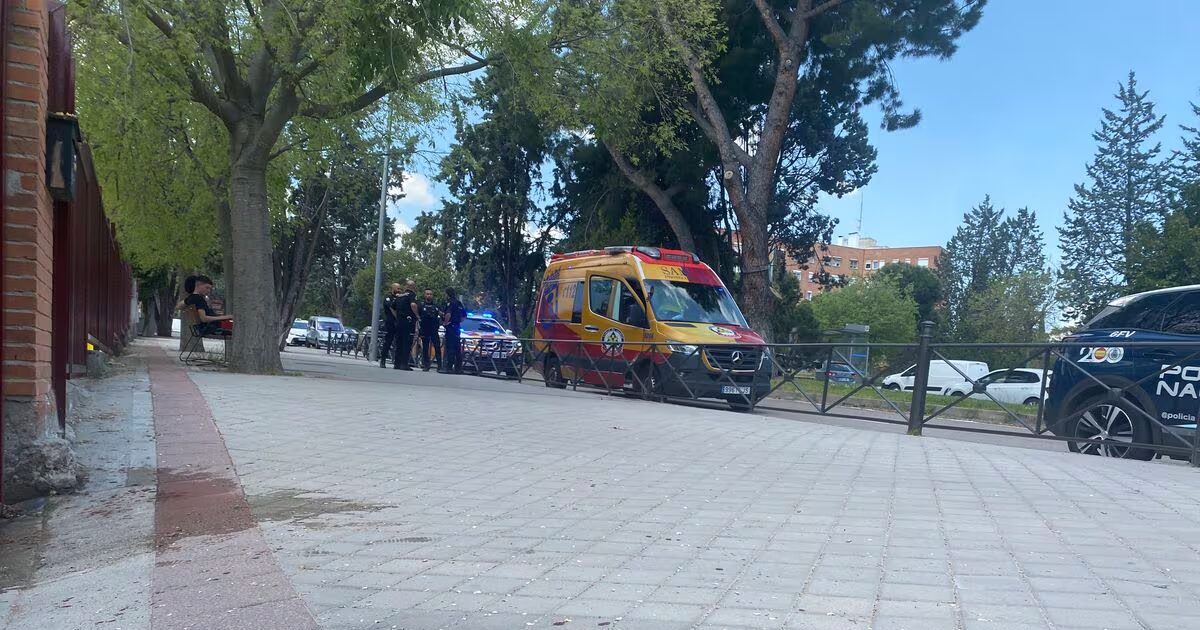La puerta del colegio en el que la víctima ha pedido ayuda, al fondo, la ambulancia que lo ha atendido.